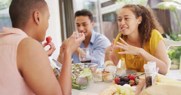 Group of diverse male and female friends laughing at dinner party on patio