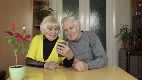 Pretty Mature Senior Couple Grandparents Making Video Call with Phone at Home