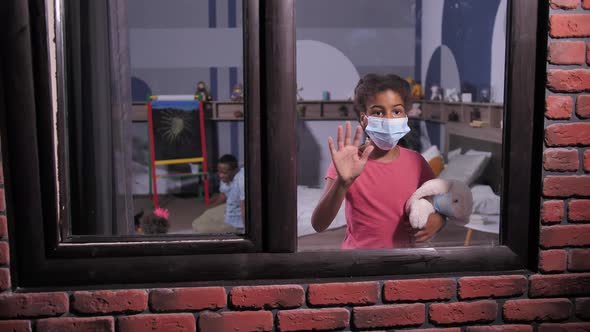 Preteen Girl in Face Mask Looking Out Window Pane