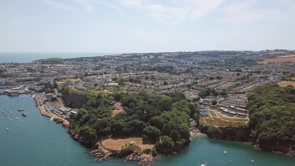 Flying over the coast of Brixham, England. Sky view of cove area on beach.