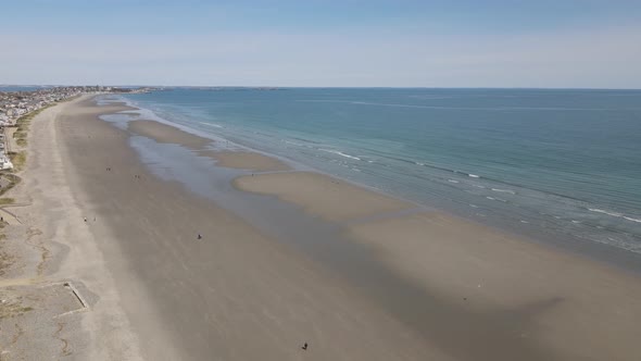 Static drone shot of a deserted beach at low tide. Atlantic Ocean, seaside community. Waves. Walkers