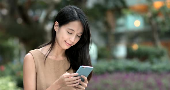 Woman using smart phone and sitting on city park