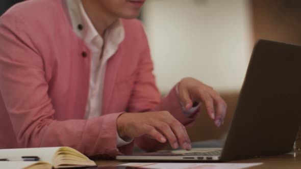 Smartly dressed asian businessman sitting at desk using laptop wondering