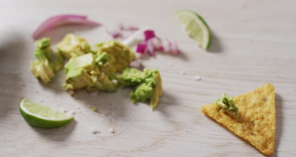 Video of tortilla chip, avocado, onion and lime on a wooden surface