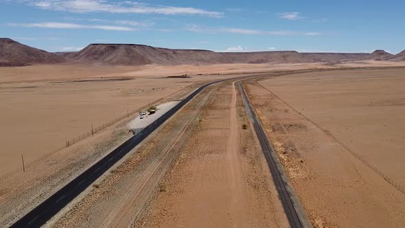 Drone footage of a modern highway with a railway next to it in Namib desert