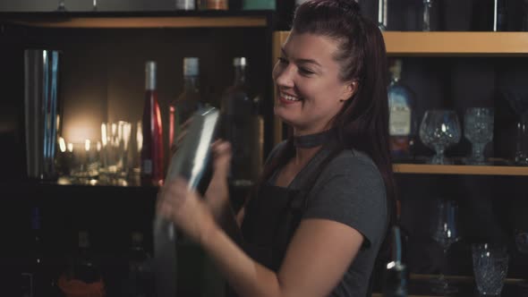 Smiling pretty female Bartender shaking Fresh Cocktails For nightlife guests in club,static