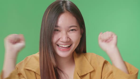 Close Up Of Cheerful Young Asian Woman Celebrating While Standing On Green Screen In The Studio