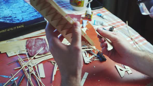 Hands of Man Adjusts Plywood Details for Ship Model Grinding on Sandpaper