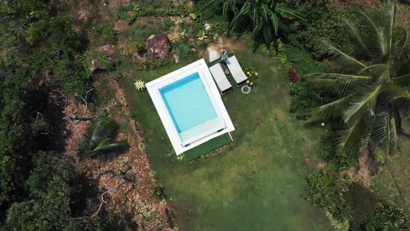 Footage of a pristine backyard swimming pool in a luxury villa. The pool and yard is surrounded by r