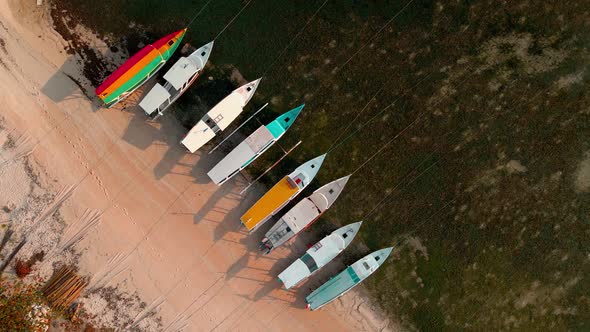 Colorful boats parking at on sandy beach during sunset on Gili Air Island.Aerial top down view.