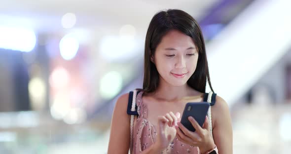 Woman use of mobile phone with shopping center background