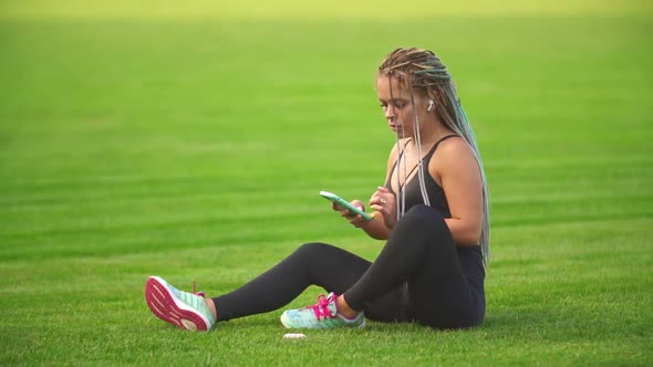 Girl with Phone Sitting on the Lawn