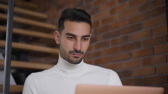 Handsome Focused Bearded Man Analyzing Emarket on Laptop Smiling