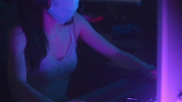 Young Woman in Headphones and White Protective Face Mask Playing an Online Game in Gaming Club