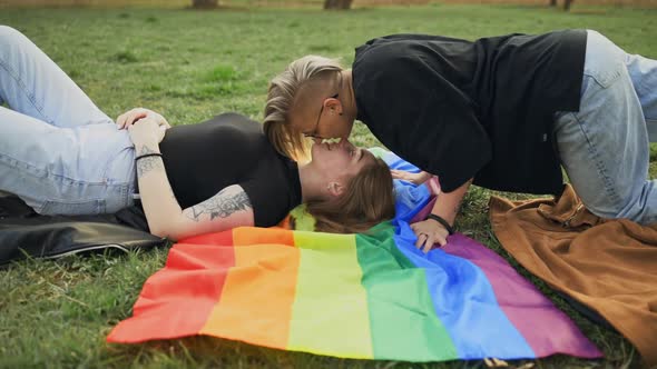 Female LGBT Couple Kissing Lying on Rainbow Flag