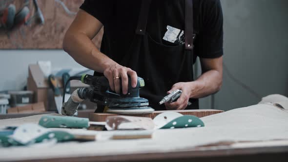 Man Worker Grinding a Wooden Piece in the Workshop Using an Instrument