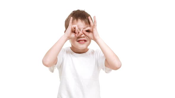 Elementaryaged Caucasian Boy Putting Hands on Face Making Funny Faces Standing on White Background