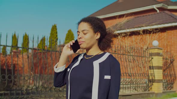 African Woman Speaking on Cellphone Walking Outdoors