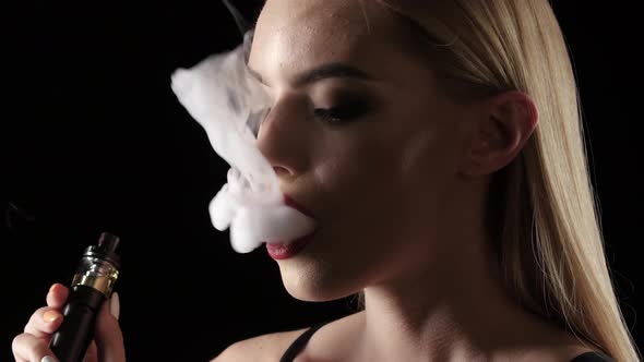 Girl Exhales Smoke and Breathes Again, Black Background. Close Up