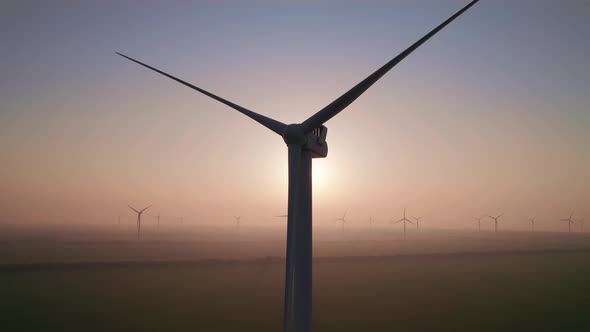 Close-up of wind turbine blades at sunset or sunrise.