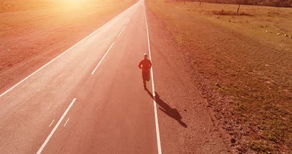 Low Altitude Flight in Front of Sporty Man at Perfect Asphalt Road