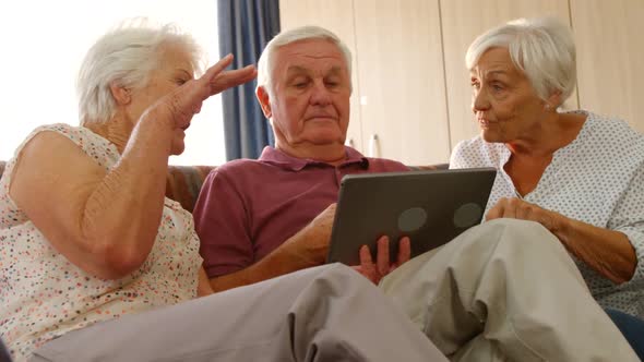 Senior friends discussing together with a digital tablet