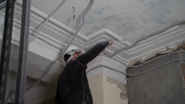 Fat Bearded Adult Man in Protective Helmet and Black Tight Fitting Clothing Remove Construction