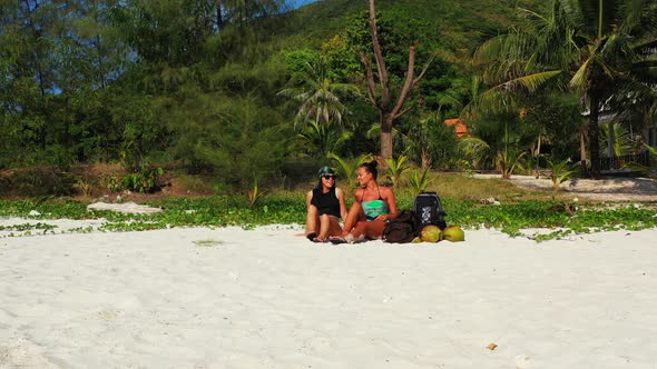 Sexy smiling ladies on vacation spending quality time at the beach on sunny blue and white sand 4K b