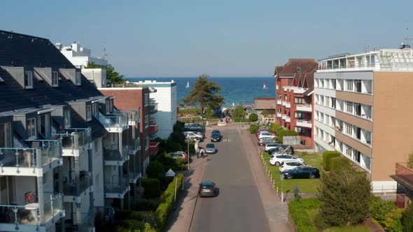 Aerial View Flying Between Building Street Facing Baltic Clear Blue Sea Water in Scharbeutz Germany