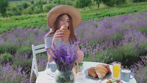 Young Woman Eating Croissant in Lavender Field