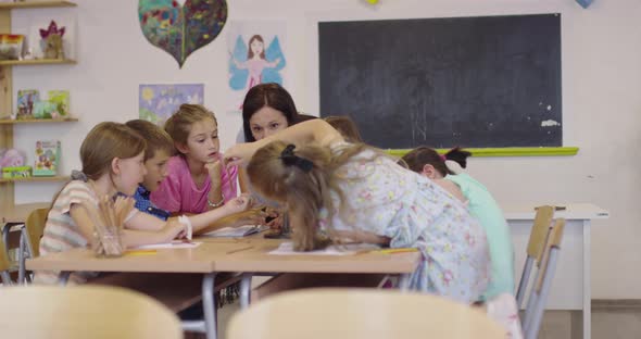 Female Teacher with Kids in Geography Class Looking at Globe