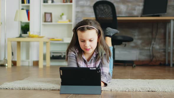 Cheerful Little Girl with Braces Lying on the Floor Carpet