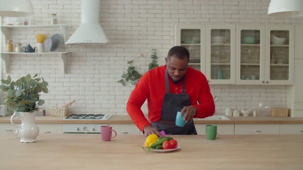 Positive Black Man in Apron Cleaning Kitchen Table