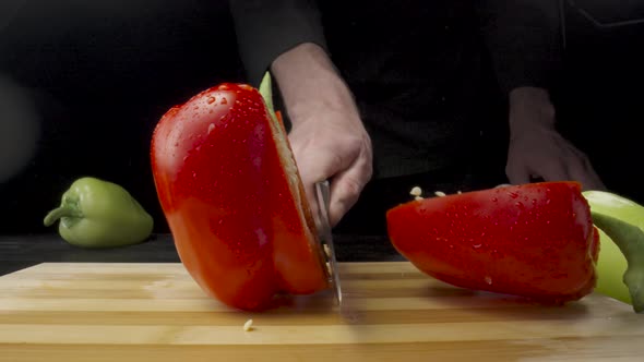 Male Hand Chop Red Sweet Pepper in Half with Sharp Knife