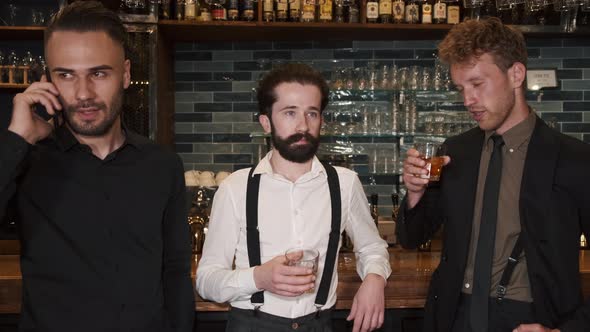 Three Business Men Standing in a Pub Against Bar Counter