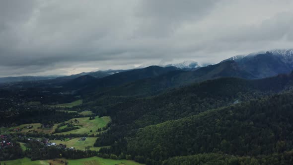 View of Mountain Valley with City in Lowland at Foot of Gently Sloping Mountains