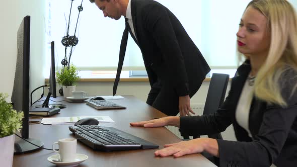 Two Office Workers, Man and Woman, Sit Down to Desks with Computers and Start Working