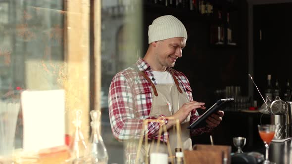 Young Male Owner Using Digital Tablet While Standing in Cafe