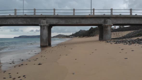 First-person shot along sandy beach and under pylon of pier