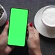 Woman holding smartphone with green screen and enjoying drinking coffee. - VideoHive Item for Sale