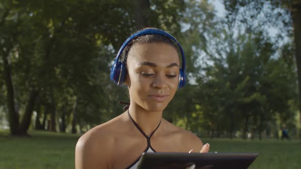 Pretty Woman in Headphones Enjoying Music in Park