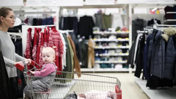 young mother with a small daughter walks in the clothing department in a supermarket