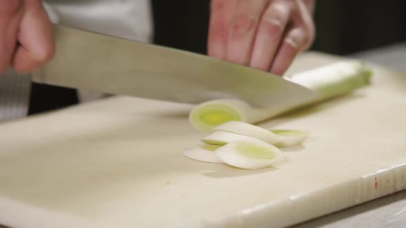 Close Up Shot of a Man's Hands, Cook Cuts a Leek on a Cutting Board, Then Pepper