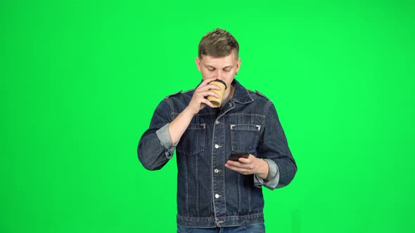 Young Man Walking and Watching on the Phone Something, Drinking Coffee, Chroma Key