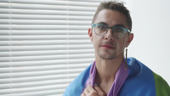 Cheerful Gay Man Wrapped in Rainbow Flag Posing for Camera