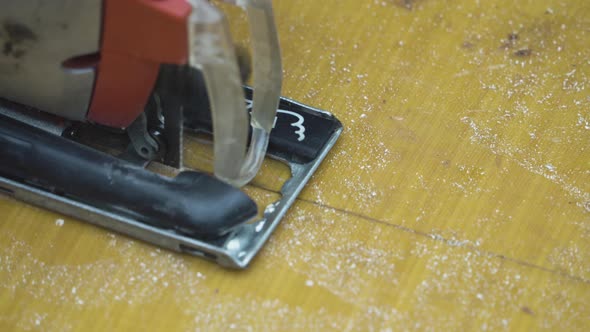 A worker cutting a sheet of fiberglass with an electric jigsaw.