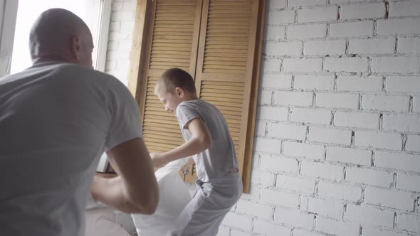 Happy Man and Boy Pillow Fighting