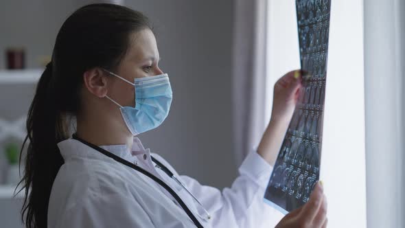 Side View Woman in Covid19 Face Mask Analyzing Xray Standing at Window Turning and Leaving