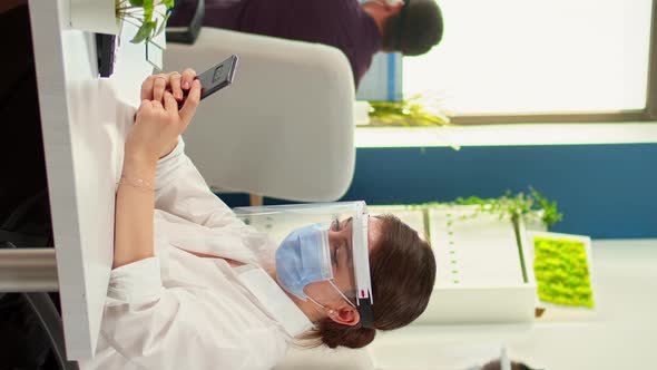 Vertical Video Businesswoman with Mask Chatting Using Phone in Office Room