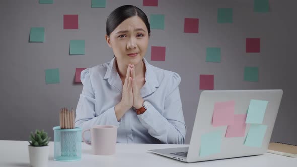 Asian woman working holding hands in prayer.